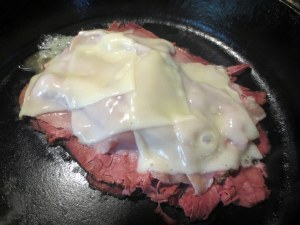 Stack 6 slices of pastrami in preheated iron skillet.  Place two slices prosciutto and top with swiss cheese.  Cover and let heat for two minutes.